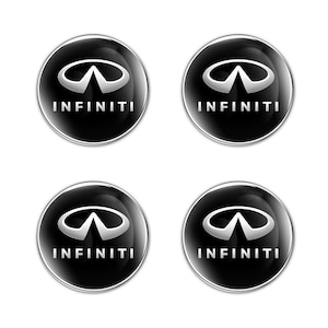 Peut inclure: Quatre emblèmes de logo Infiniti noirs et argentés. Chaque emblème est circulaire avec un fond noir brillant. Le logo Infiniti est un double arc argenté stylisé, avec le mot "INFINITI" en argent en dessous.