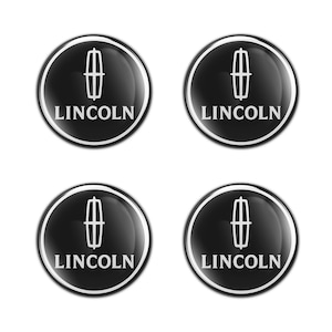 May include: Four glossy black and silver Lincoln emblem stickers. Each circular sticker features the Lincoln logo, a vertical emblem, and the brand name in white, set against a black background.