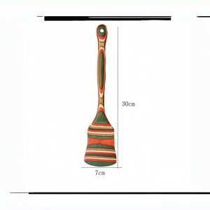 May include: A wooden spatula with a long handle and a wide, flat head. The spatula is 11.8 inches long and 2.8 inches wide, featuring a striped pattern in shades of green, orange, and brown. It has a hole in the handle for hanging.