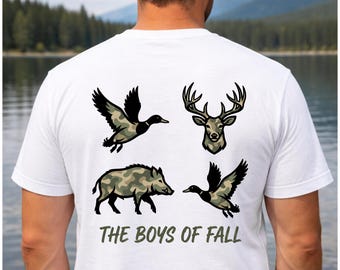 May include: A white short-sleeved t-shirt featuring a graphic on the back with four camouflage-patterned animals: a flying duck, a deer head, a wild boar, and another flying duck. Below the animals, the text reads THE BOYS OF FALL in green.