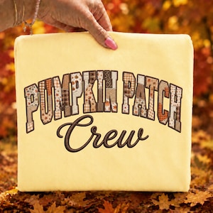 May include: A pale yellow sweatshirt featuring the text PUMPKIN PATCH in a blocky, brown-outlined font filled with various autumn-themed patterns, including plaid, leopard print, and leaves. Below, the word Crew is embroidered in brown script.