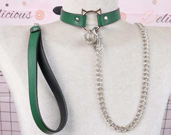 May include: Green and black choker collar with a cat ear design, a silver chain, and a matching leash. The collar features a silver bell and a clasp. The leash is green on one side and black on the other.