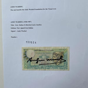 Puede incluir: Una obra de arte firmada de Andy Warhol con un billete italiano de 500 liras. La obra incluye la firma del artista y el texto "REPUBBLICA ITALIANA CINQUECENTO". La obra está sobre un fondo blanco.