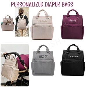 May include: Collection of personalized diaper bags in various colors, including beige, burgundy, gray, and black. Each bag features a top handle, front pockets, and the name of a child embroidered on the front. The bags are shown in different settings.