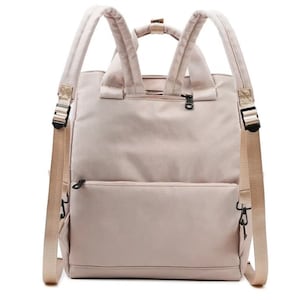 May include: A light beige backpack with adjustable shoulder straps and a top handle. The bag features a front zippered pocket and a main compartment with a zipper closure. The straps and handle are a lighter beige color, and the hardware is black.