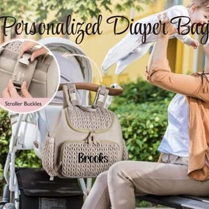 May include: A beige diaper bag backpack with a zipper closure and the name "Brooks" embroidered on the front. The bag has stroller straps and is shown attached to a stroller.