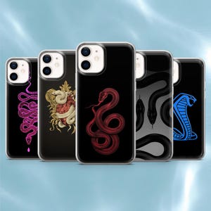 Op de afbeelding: Vijf doorzichtige telefoonhoesjes met verschillende slangenillustraties. De ontwerpen bevatten een roze geometrische slang, een witte slang rond een hart, een rode slang, een zwart slangenpatroon en een blauwe cobra op een zwarte achtergrond.