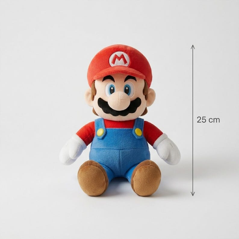 Puede incluir: Un peluche de Mario, de aproximadamente 25 cm de altura, con gorra roja con 'M' blanco, camisa roja, peto azul y zapatos marrones. El mu&ntilde;eco tiene un gran bigote negro y guantes blancos, sobre un fondo neutro.