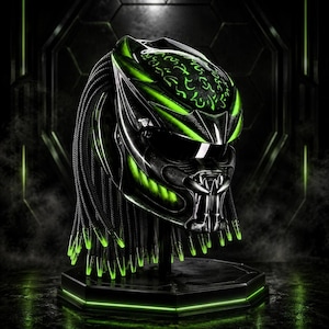 May include: A black motorcycle helmet featuring a stylised alien-inspired design with vibrant neon green accents and glowing symbols on the top. The helmet includes long black dreadlock-style strands with neon green tips and a dark visor.