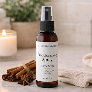 Könnte beinhalten: Eine braune Glasflasche "Deodorizing Spray" von "The Crystal Garden" mit schwarzem Verschluss. Das Etikett lautet "Home Spice" und "Nettoinhalt 57g." Zimtstangen und ein Sternanis liegen vor der Flasche.