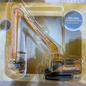 May include: A yellow and black model excavator toy with the text "Stobart Rail" and "Civil Engineering". The toy is packaged in a clear plastic container with the "Oxford Construction" logo.