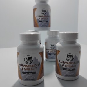Op de afbeelding: Verschillende witte supplementflessen met de tekst "RAW ASHWAGENDHA & SHILAJIT 500MG" zijn afgebeeld. De etiketten hebben een berg-afbeelding en een bruin-wit ontwerp. De flessen bevatten 60 capsules.