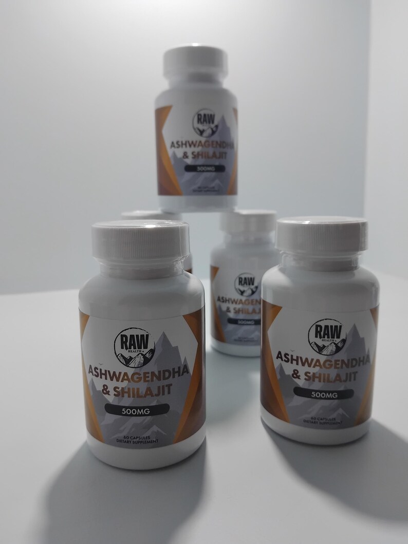 Op de afbeelding: Verschillende witte supplementflessen met de tekst "RAW ASHWAGENDHA & SHILAJIT 500MG" zijn afgebeeld. De etiketten hebben een berg-afbeelding en een bruin-wit ontwerp. De flessen bevatten 60 capsules.