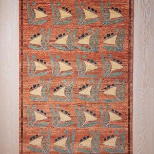 May include: A rectangular rug with a repeating pattern of stylized sailboat motifs. The rug features a warm, reddish-orange background with cream-colored sails, teal accents, and black dots. The rug has a border.