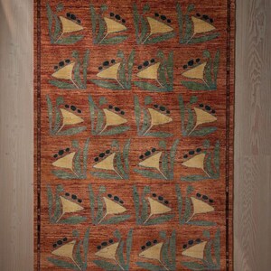 May include: Rectangular area rug with a repeating pattern of stylized sailboats in yellow, green, and black on a reddish-brown background. The rug has a border and is made of a woven material.