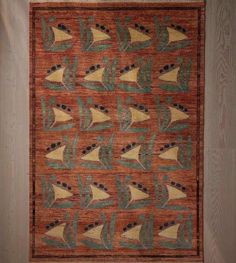 May include: Rectangular area rug with a repeating pattern of stylized sailboats in yellow, green, and black on a reddish-brown background. The rug has a border and is made of a woven material.