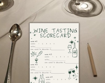 May include: A wine tasting scorecard with illustrations of wine glasses and bottles, along with space to score and write notes. A silver spoon, a pencil, and wine glasses are also on the white tablecloth.