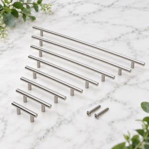 May include: A collection of seven silver-toned cylindrical cabinet pulls arranged in ascending order of length, featuring a smooth metallic finish and two small matching screws positioned to the side for installation purposes.