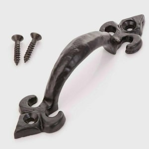 May include: A black, ornate door pull with a fleur-de-lis design. The handle is curved and textured, with decorative ends. Two black screws are included. Suitable for cabinets, drawers, or doors.