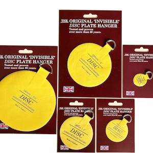 May include: A selection of yellow adhesive disc plate hangers, each with a metal ring and packaged on maroon cards. The packaging features the text "THE ORIGINAL 'INVISIBLE' DISC PLATE HANGER" and the Union Jack flag. Sizes range from 75mm to 190mm.
