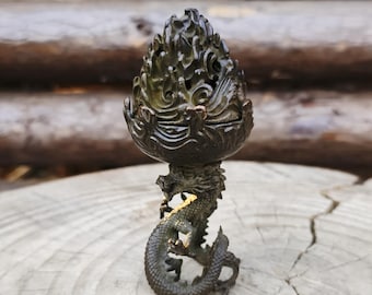May include: A bronze-colored incense burner with a dragon base. The burner has a detailed, flame-like top with intricate cutouts. The dragon is coiled around the base, adding a mythical element to the decor.
