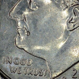 May include: Close-up of a United States dime coin. The coin features a profile of a man, the words "IN GOD WE TRUST", and the year 2018. The coin is silver in color and shows signs of wear.