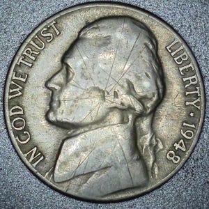 May include: A close-up of a silver coin. The coin features a profile of a man, the words "IN GOD WE TRUST" and "LIBERTY 1948". The coin is slightly worn with visible scratches.