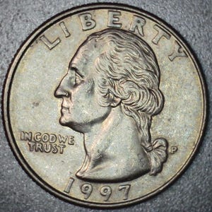 May include: A United States quarter coin from 1997. The obverse features a profile of George Washington, the words "LIBERTY" and "IN GOD WE TRUST". The coin is silver in color.
