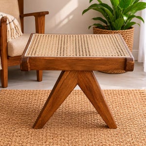 May include: A square side table constructed from medium-toned brown wood featuring a flat top with a woven cane inlay. The table is supported by a V-shaped base with two angled legs that meet at the center, providing a stable foundation for the piece.