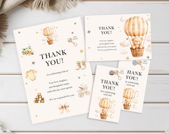 Może przedstawiać: Zestaw kartek z podziękowaniami na baby shower z motywem balonu na ogrzane powietrze i misia. Kartki zawierają napis "THANK YOU!" oraz inne ilustracje związane z dzieckiem w miękkich, neutralnych kolorach. Ułożone na białej drewnianej powierzchni.