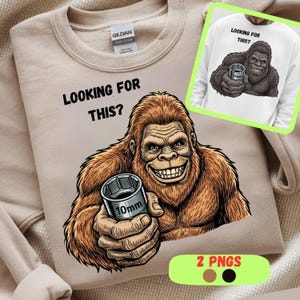 Könnte beinhalten: Beiges Sweatshirt mit einem Cartoon-Gorilla, der einen 10-mm-Steckschlüssel hält. Der Text "LOOKING FOR THIS?" steht über dem Gorilla. Ein kleineres Bild des Designs befindet sich in der oberen rechten Ecke. Das Sweatshirt hat einen Rundhalsausschnitt.