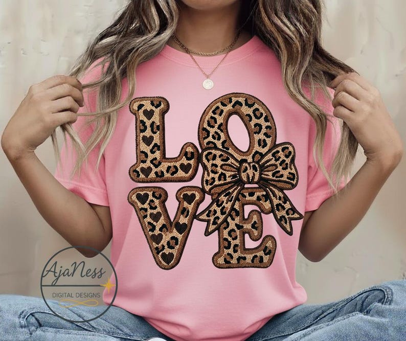 May include: A pink t-shirt with the word "LOVE" in a leopard print design and heart accents. The "O" is a bow. The shirt also has the text "AjaNess DIGITAL DESIGNS" in a circle at the bottom left.
