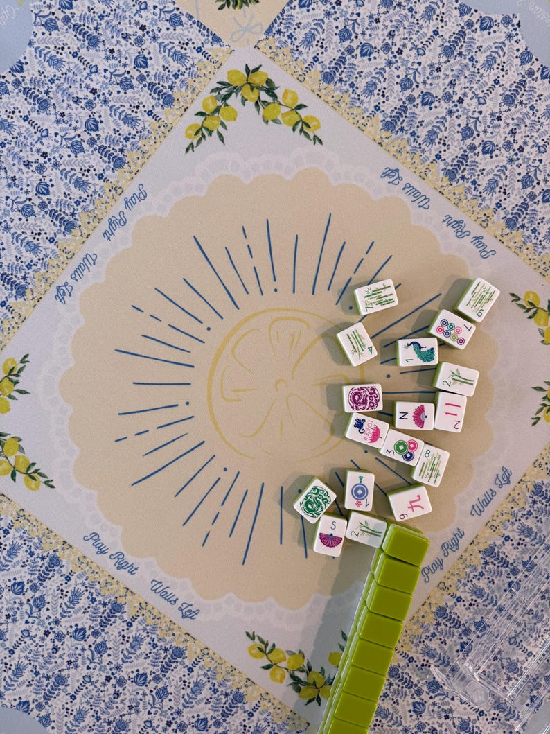 Puede incluir: Vista superior de un juego de Mahjong. El tablero presenta un dise&ntilde;o de lim&oacute;n con el texto "Play Right Walls Left". Las fichas dispersas muestran varios s&iacute;mbolos y n&uacute;meros. Un soporte verde para fichas est&aacute; en primer plano.