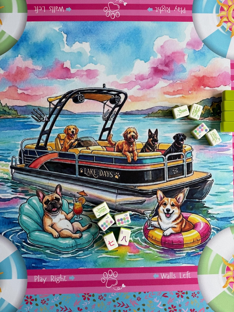 May include: A colorful game mat featuring a watercolor illustration of dogs on a pontoon boat labeled Lake Days, with a French Bulldog and a Corgi floating in the water on inflatable rings, surrounded by scattered mahjong tiles and pink clouds.