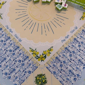 Puede incluir: Un juego de Mahjong con un dise&ntilde;o de tem&aacute;tica de lim&oacute;n. El tablero presenta un centro amarillo con una ilustraci&oacute;n de rodaja de lim&oacute;n y bordes con motivos florales azules. Las fichas verdes y blancas est&aacute;n esparcidas por el tablero.