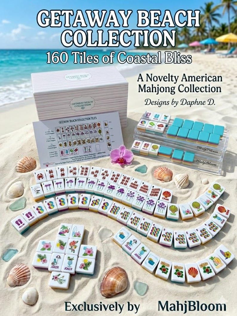 May include: A Getaway Beach Collection American Mahjong set featuring 160 white tiles with colorful coastal illustrations, a storage box, a reference card, and two clear acrylic tile racks, all displayed on a sandy beach with seashells.