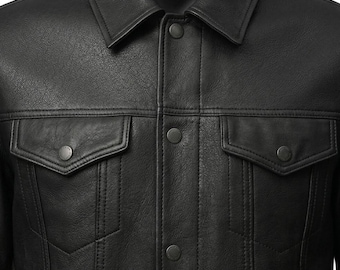 May include: A black jacket featuring a classic collar, a front button placket with matching black buttons, and two chest pockets with buttoned flaps. The garment is constructed with visible vertical seam detailing and a textured finish.