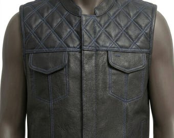 May include: A black leather vest featuring a diamond-quilted pattern across the upper chest and shoulders. The garment includes two chest pockets with flaps and a mandarin collar, accented with visible blue stitching throughout the design.