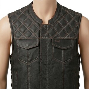 Puede incluir: Un chaleco de cuero marrón oscuro con un patrón de diamantes acolchado en la parte superior del pecho y los hombros. La prenda incluye dos bolsillos en el pecho con solapas, un cuello redondo y costuras de contraste visibles.
