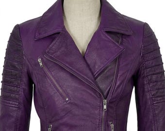 May include: A vibrant purple jacket featuring a classic notched lapel collar, an asymmetrical front zipper closure, and three additional zippered pockets. The sleeves are designed with horizontal quilted detailing on the upper arm sections.