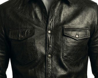 May include: A black long-sleeve shirt with a textured, crinkled finish. The shirt features a classic collar, a central button-down placket with metallic snap buttons, and two chest pockets with matching snap-button flaps on the left and right sides.