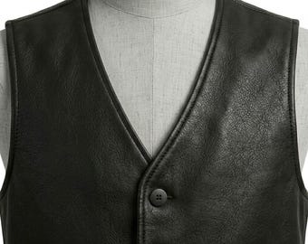 May include: A black leather vest featuring a V-neckline and a front button closure with two visible circular black buttons. The vest is displayed on a light gray mannequin torso, highlighting the textured surface of the leather material.