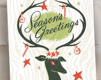 May include: A vintage Christmas card with a green and white striped background. The card features a stylized deer with antlers and the text "Season's Greetings".