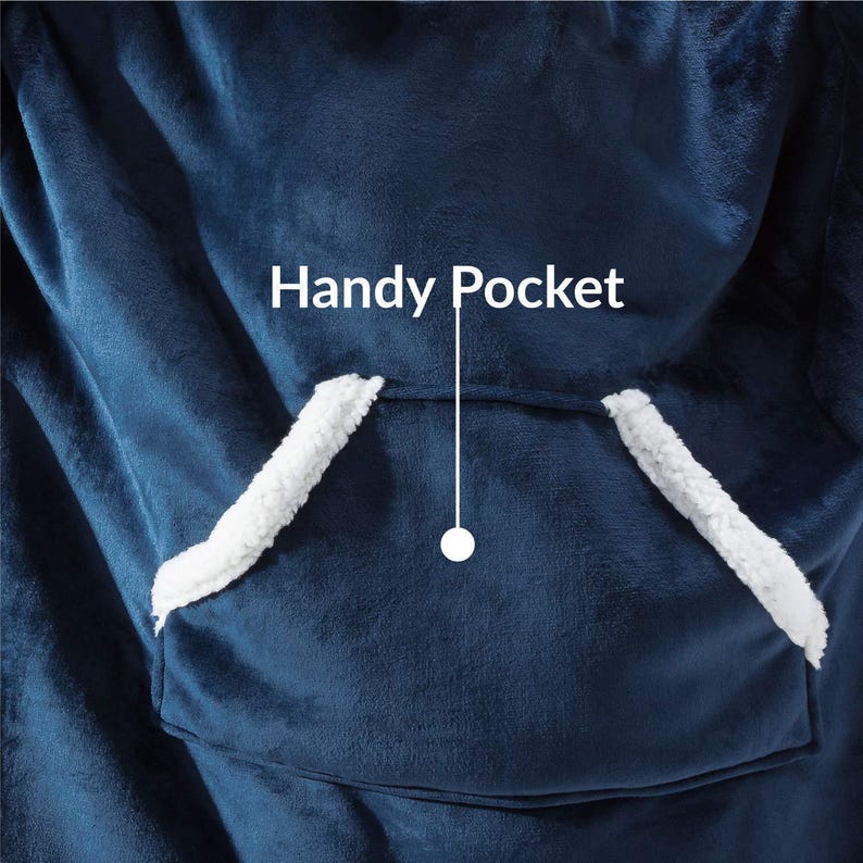 Peut inclure: Gros plan d'une couverture portable bleu marine avec une grande poche avant. La poche est bord&eacute;e d'un mat&eacute;riau blanc et duveteux. Le texte "Handy Pocket" est au-dessus de la poche.