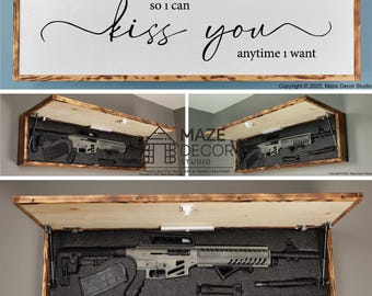 Puede incluir: Una caja de almacenamiento rectangular de madera para pared con un panel frontal abatible que muestra el texto "so I can kiss you anytime I want". El interior contiene un rifle gris con cargador negro y accesorios en espuma.
