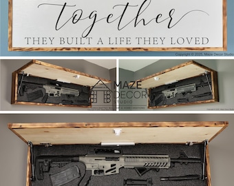 Puede incluir: Una caja de ocultación rectangular de madera para pared con un panel frontal abatible que muestra el texto AND SO TOGETHER THEY BUILT A LIFE THEY LOVED. El interior contiene espuma oscura para sujetar un rifle y accesorios.