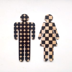 Puede incluir: Dos figuras de madera, una con un patrón de lunares blanco y negro y la otra con un patrón de cuadros blanco y negro.