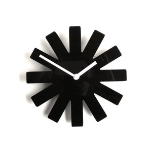 May include: Black clock with white hands and a unique sunburst design. The clock face is black and the hands are white.
