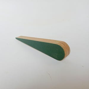 May include: A wooden nail file with a green sanding surface. The file is tapered and has a rounded end.