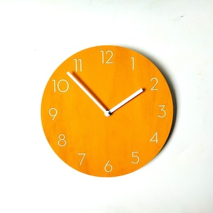 Oranje houten wandklok met cijfers. Unieke kleurrijke moderne stille analoge klok uit het midden van de eeuw voor de keuken, woonkamer of slaapkamer
